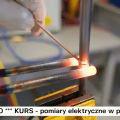 Ręka w rękawiczce wykonuje lutowanie miedzi. Dwa rozgrzane do czerwoności miedziane przewody są łączone za pomocą cienkiego drutu.