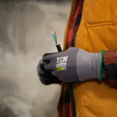 Elektryk w rękawicach trzyma kabel z odsłoniętymi przewodami.