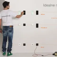 Mężczyzna pokazuje na jakiej wysokości gniazdka powinny być montowane: 150 cm dla informacji, 110-120 cm dla akcji i 30 cm dla zasilania.