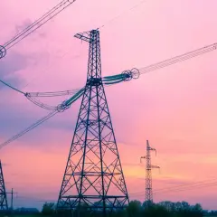 Wieże energetyczne na tle różowego nieba. Linie wysokiego napięcia, które przenoszą energię elektryczną o określonej częstotliwości napięcia, tworzą malowniczy krajobraz.