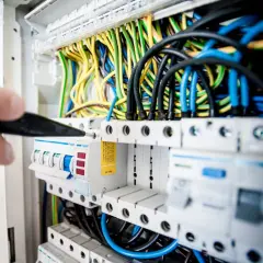 Ręka z narzędziem przy skrzynce z bezpiecznikami. Sprawdzanie instalacji elektrycznej to pierwszy krok, jak sprawdzić gdzie jest awaria prądu.