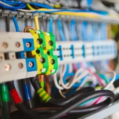 Kolorowe przewody w skrzynce elektrycznej, w tym zielono-żółty przewód uziemienia, łączą się z zaciskami.