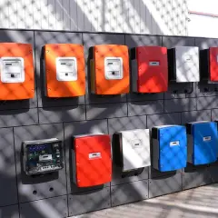 Rząd kolorowych skrzynek, w tym pomarańczowe, czerwone, białe i niebieskie, to falowniki. Jeden z nich jest otwarty, ukazując elektronikę.