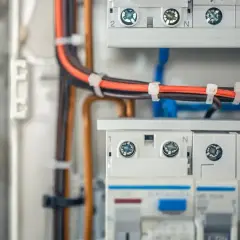 Nowoczesna instalacja elektryczna bezpuszkowa z przewodami w kolorach czarnym i pomarańczowym, uporządkowanymi opaskami.