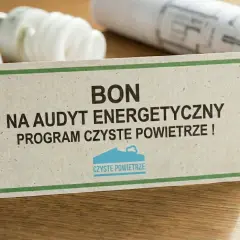 Bon na audyt energetyczny w ramach programu Czyste Powietrze. Na stole leżą żarówki i projekt.