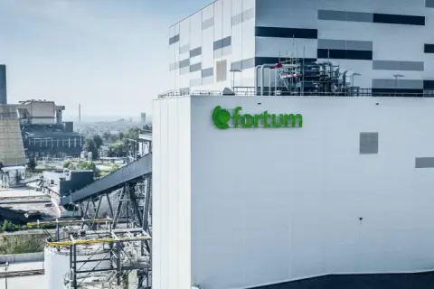 Nowoczesna elektrociepłownia Fortum, gdzie powstaje zielony prąd, z charakterystycznym logo. W tle widać kominy i chłodnie kominowe.