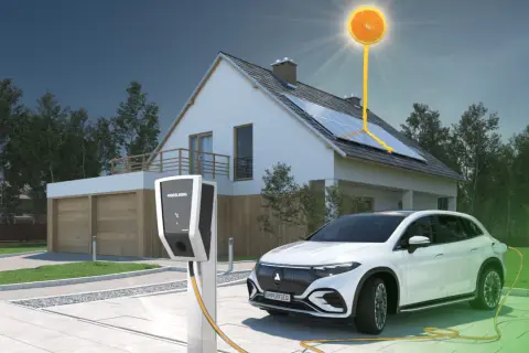 Biały samochód elektryczny jest podłączony do ładowarki przy nowoczesnym domu z panelami słonecznymi. Słońce w kształcie pomarańczy symbolizuje czystą energię.