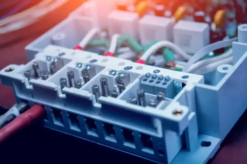 Wnętrze skrzynki elektrycznej z przewodami i złączami. Widać śruby i zaciski, które łączą kable. THD.