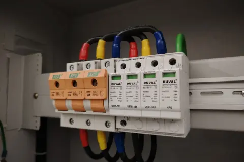 W skrzynce elektrycznej zamontowano przepięciówkę, chroniącą instalację przed nagłymi skokami napięcia. Widać trzy pomarańczowe bezpieczniki i białe moduły ochronne.