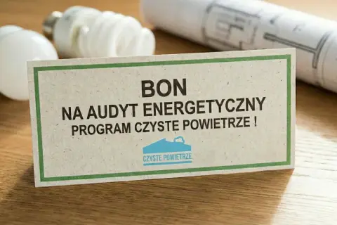 Bon na audyt energetyczny w ramach programu Czyste Powietrze. Na stole leżą żarówki i projekt.