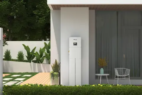 Nowoczesny magazyn energii 5 kW, idealny do zasilania domu. Obok drzwi wejściowych i okna, otoczony zielenią.