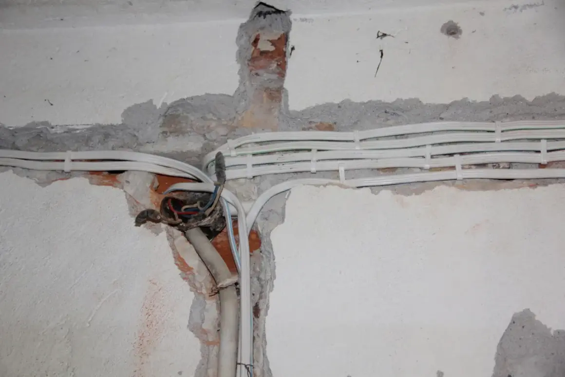 Nowe kable elektryczne w ścianie, przygotowanie do wymiany instalacji elektrycznej. Widoczne przewody i puszka instalacyjna.
