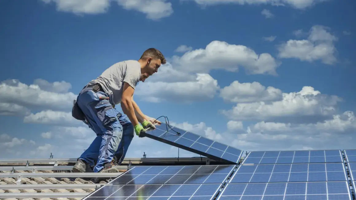 Instalator montuje panele fotowoltaiczne na dachu. Dbałość o szczegóły i ekologiczne rozwiązania dla każdego prosumenta.