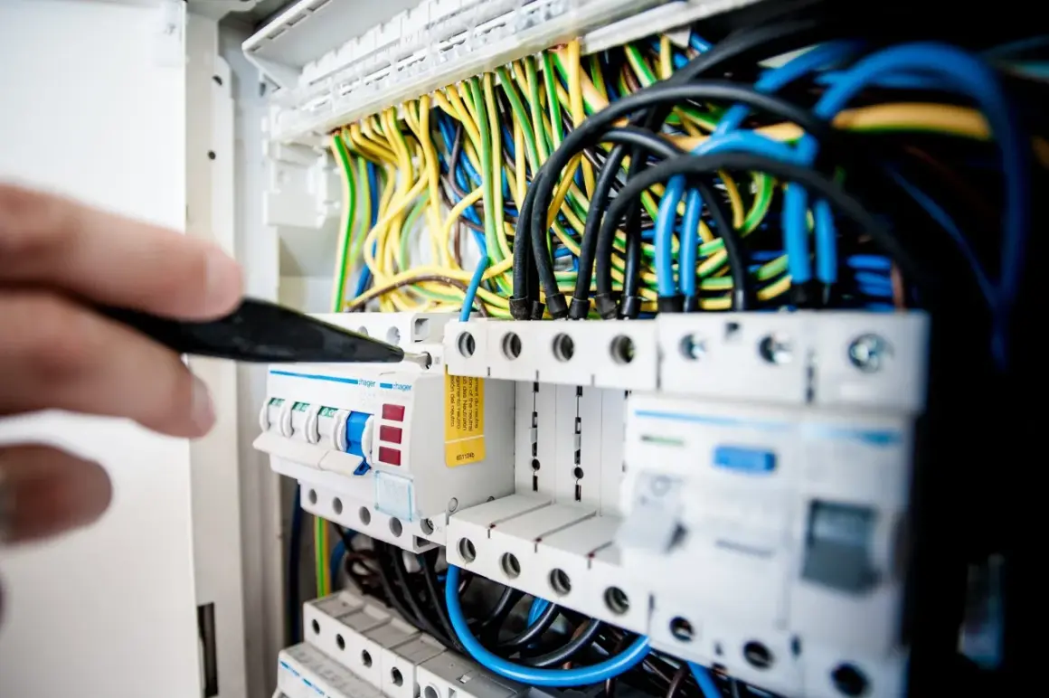 Ręka z narzędziem przy skrzynce z bezpiecznikami. Sprawdzanie instalacji elektrycznej to pierwszy krok, jak sprawdzić gdzie jest awaria prądu.