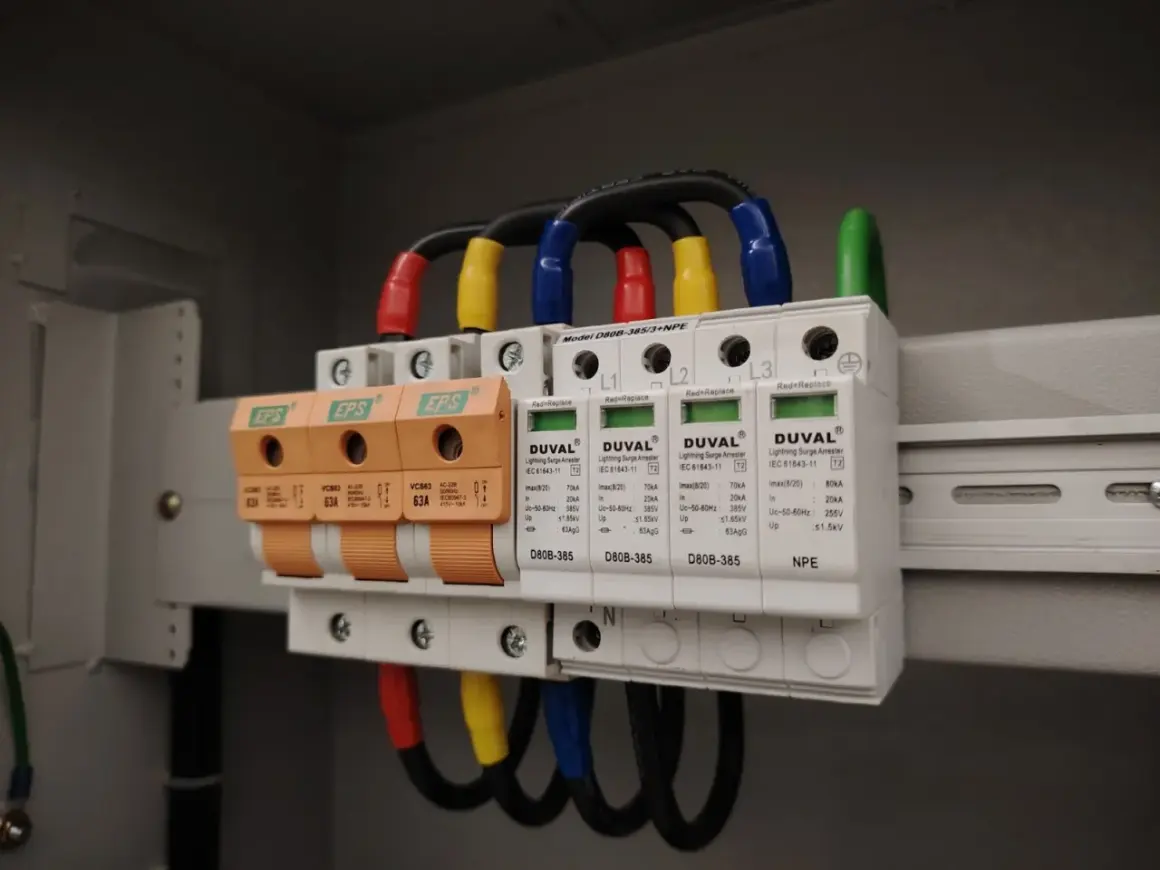 W skrzynce elektrycznej zamontowano przepięciówkę, chroniącą instalację przed nagłymi skokami napięcia. Widać trzy pomarańczowe bezpieczniki i białe moduły ochronne.