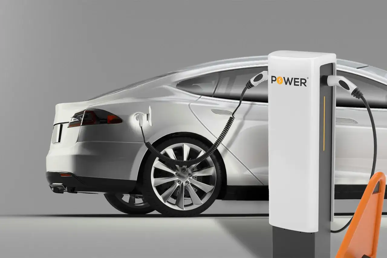Srebrny samochód elektryczny w trakcie ładowania. Stacja ładująca z logo