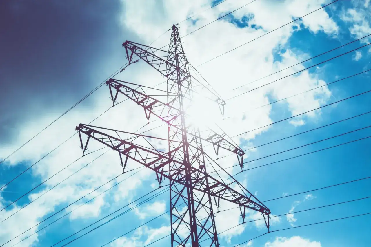 Słońce przebija się przez chmury, oświetlając linię energetyczną. Czy aluminium przewodzi prąd? Tak, to właśnie dzięki niemu mamy energię.