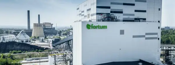 Nowoczesna elektrociepłownia Fortum, gdzie powstaje zielony prąd, z charakterystycznym logo. W tle widać kominy i chłodnie kominowe.