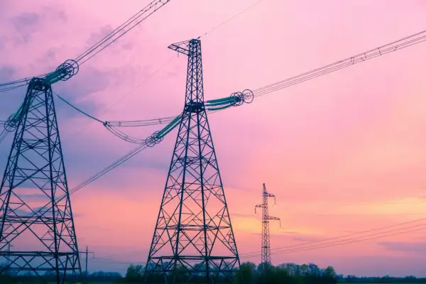 Wieże energetyczne na tle różowego nieba. Linie wysokiego napięcia, które przenoszą energię elektryczną o określonej częstotliwości napięcia, tworzą malowniczy krajobraz.