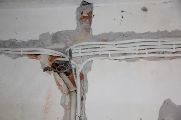 Nowe kable elektryczne w ścianie, przygotowanie do wymiany instalacji elektrycznej. Widoczne przewody i puszka instalacyjna.